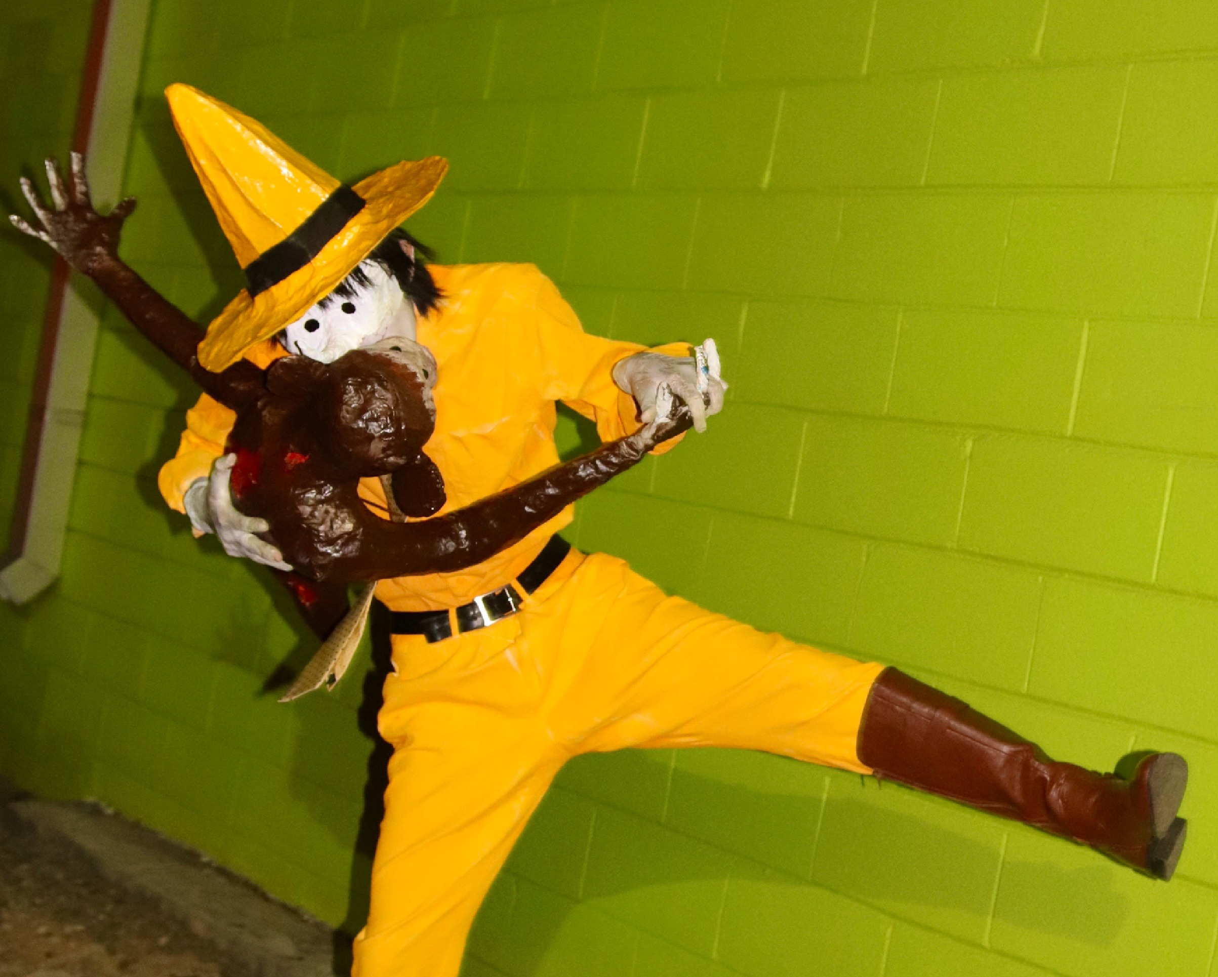 A man in a yellow hat making out with a monkey