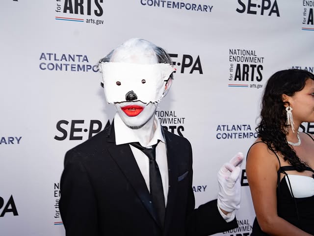 A balding white clown looks at the camera